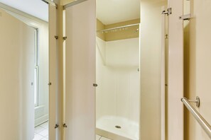 A bathroom with a glass-enclosed shower, a white bathtub, and a door leading to another room. - ATL Commuter's Dream! 1/2 Mi to MARTA in Decatur (Decatur)