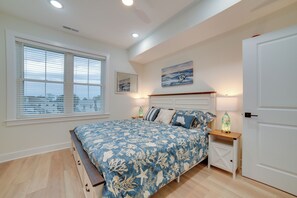 Ein Schlafzimmer mit einem Bett, einem Nachttisch, einer Lampe, einem Fenster mit Jalousien und einer Tür.