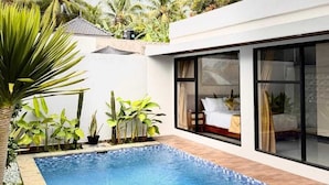 Una casa moderna con piscina, ventanas amplias y plantas tropicales.