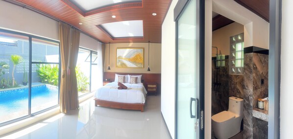 Une chambre moderne avec un grand lit, une vue sur une piscine et une salle de bain avec un mur en marbre.