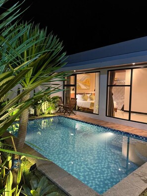 Une maison moderne dotée d’une piscine, de grandes fenêtres et d’un intérieur bien éclairé.