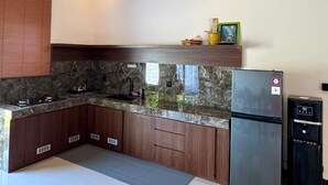 Una cocina moderna con armarios de madera oscura, encimera de granito, refrigerador de acero inoxidable y horno empotrado.