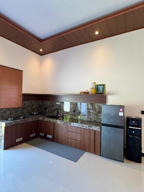 Eine moderne Küche mit dunklen Holzschränken, einer Granit-Arbeitsplatte, einem Edelstahl-Kühlschrank und einem eingebauten Ofen.