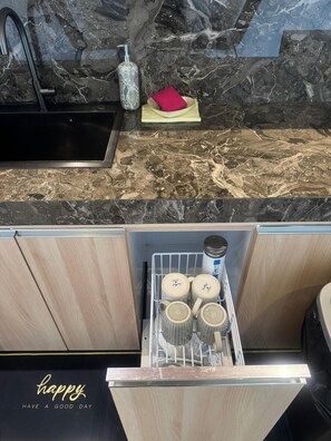 Une cuisine dotée d’un plan de travail en marbre, d’un évier et d’un égouttoir à vaisselle avec des tasses.
