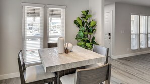 A dining area with a table, chairs, a ceiling fan, and a large plant. - Grand Prix Energy 1 Mi From the Strip (Las Vegas)