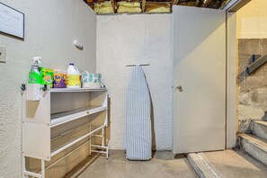Et bryggers med en hvid reol med rengøringsartikler, et stribet håndklæde hængende på en bøjle, og en lukket dør.