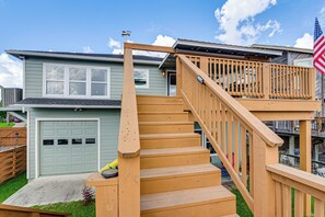 A residential house with a wooden staircase leading to a deck, a garage, and a clear sky. - Elegant Waterfront Retreat w/ Dock in Dickinson (Dickinson)
