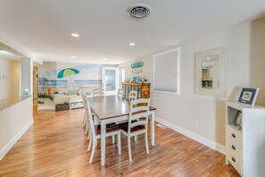 A dining area with a view of the beach, a ceiling vent, and a sideboard with decorative items. - Kim G's Bayside Cottage: Montego Bay (Ocean City)