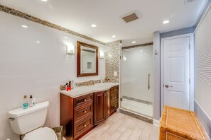A bathroom with a toilet, vanity, mirror, and shower. - Kim G's Bayside Cottage: Montego Bay (Ocean City)
