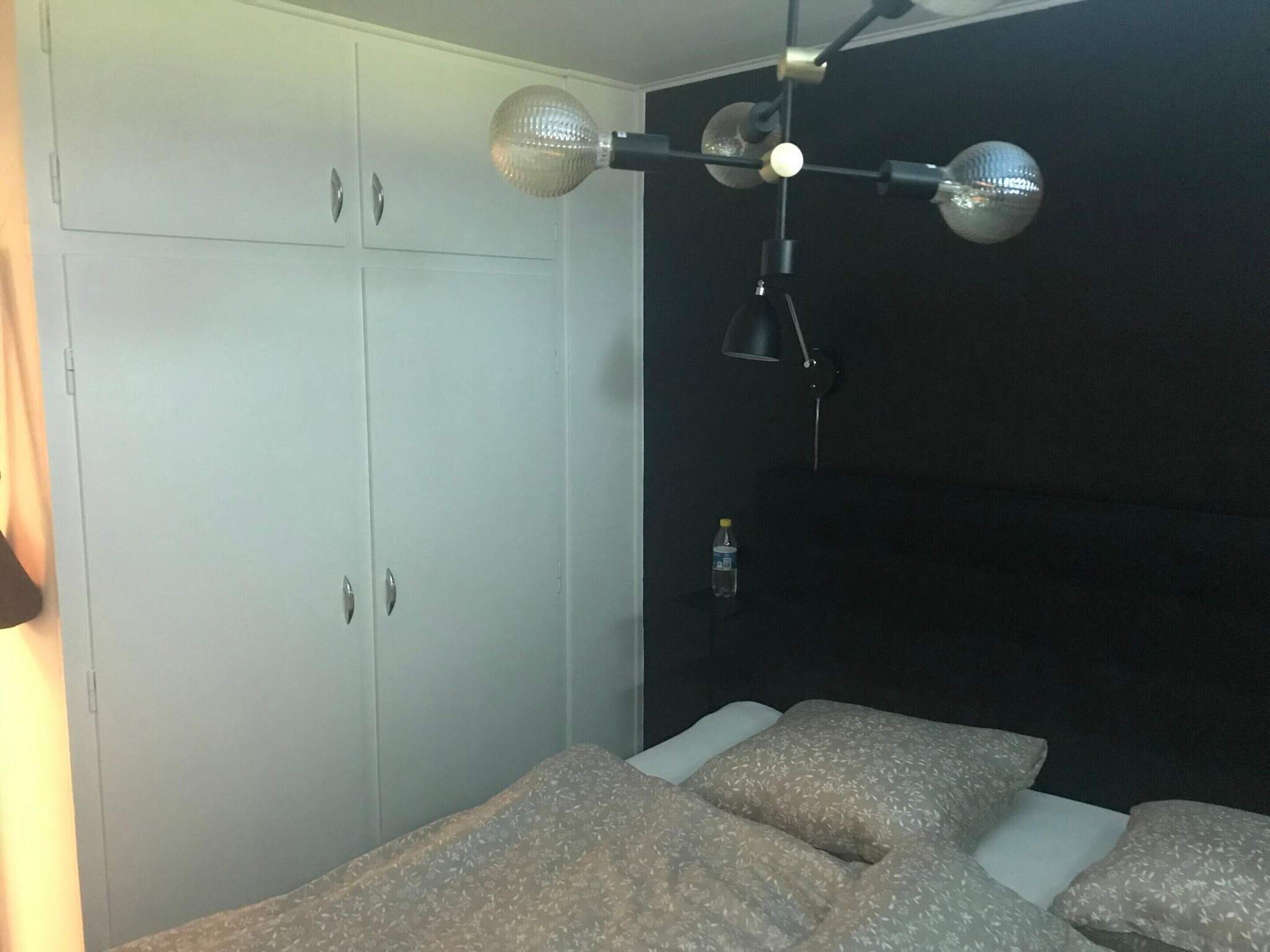 Une chambre à coucher avec un lit, une armoire et une lampe suspendue.