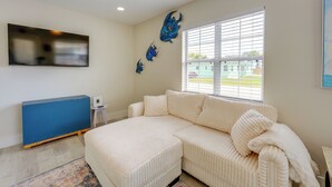 Una sala de estar moderna con un sofá seccional, un televisor de pantalla plana y decoración mural.