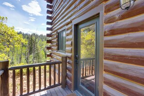 Une cabane en rondins avec une terrasse en bois et une porte en verre.