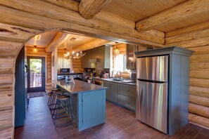 Une cuisine de style rustique, avec un îlot central, des tabourets de bar, des appareils en acier inoxydable et un plafond en bois.