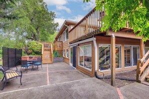 A wooden deck with outdoor furniture, a covered patio area, and a large windowed section of the building.