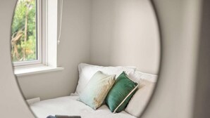 A room with a window, a bed with pillows, and a view of greenery outside. - Flat 3, Franklin Apt Reading (Berkshire)
