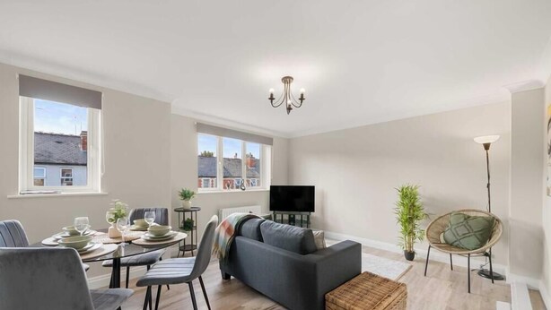 A spacious living room with a sofa, dining table, and chairs, a flat-screen TV, and large windows with a city view. - Flat 3, Franklin Apt Reading (Berkshire)