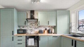 A kitchen with light green cabinets, a microwave, toaster, and a stove. - Flat 3, Franklin Apt Reading (Berkshire)
