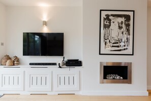Ein Wohnzimmer mit Flachbildfernseher, Kamin und einem Bilderrahmen mit Schwarz-Weiß-Kunstwerk.