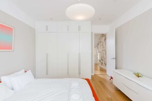 Ein modernes Schlafzimmer mit einem Bett, einem weißen Kleiderschrank und einem Flur, der in einen anderen Raum führt.