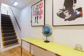 A staircase with a handrail, a yellow table with a mirror, and two framed artworks on the wall. - Colourful 3BDR Garden Maisonette in North London (Greater London)