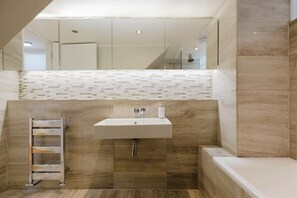 Ein modernes Badezimmer mit Waschbecken, Spiegel und Dusche.