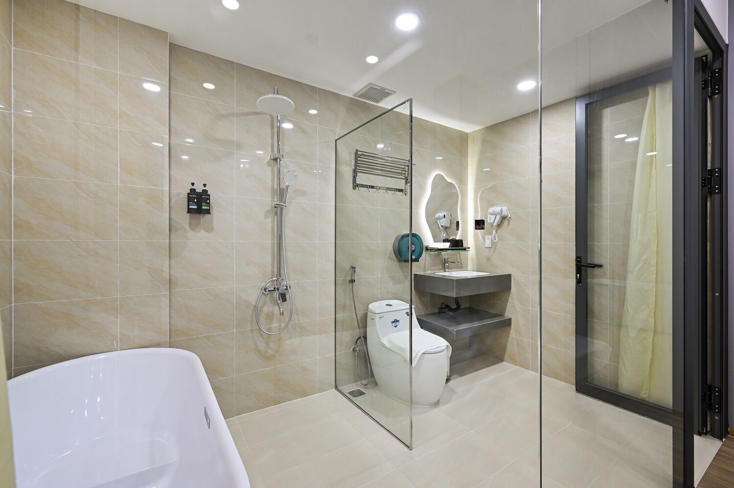 Un baño moderno con ducha de vidrio, una bañera blanca y un tocador con espejo.