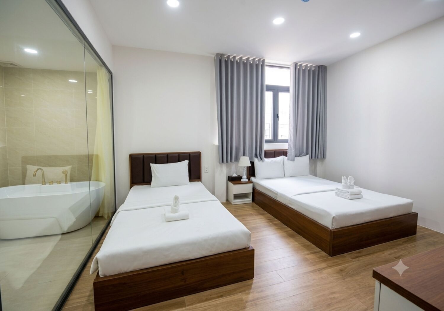 A hotel room with two beds, a bathtub, and a window with curtains.