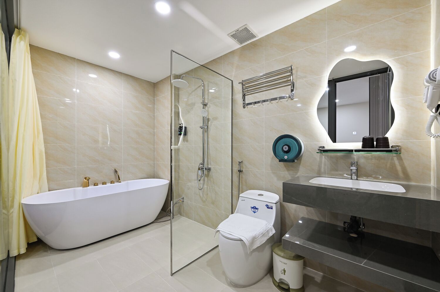Une salle de bain moderne avec une baignoire sur pieds, une douche à parois de verre, des toilettes et un meuble-lavabo avec un miroir.