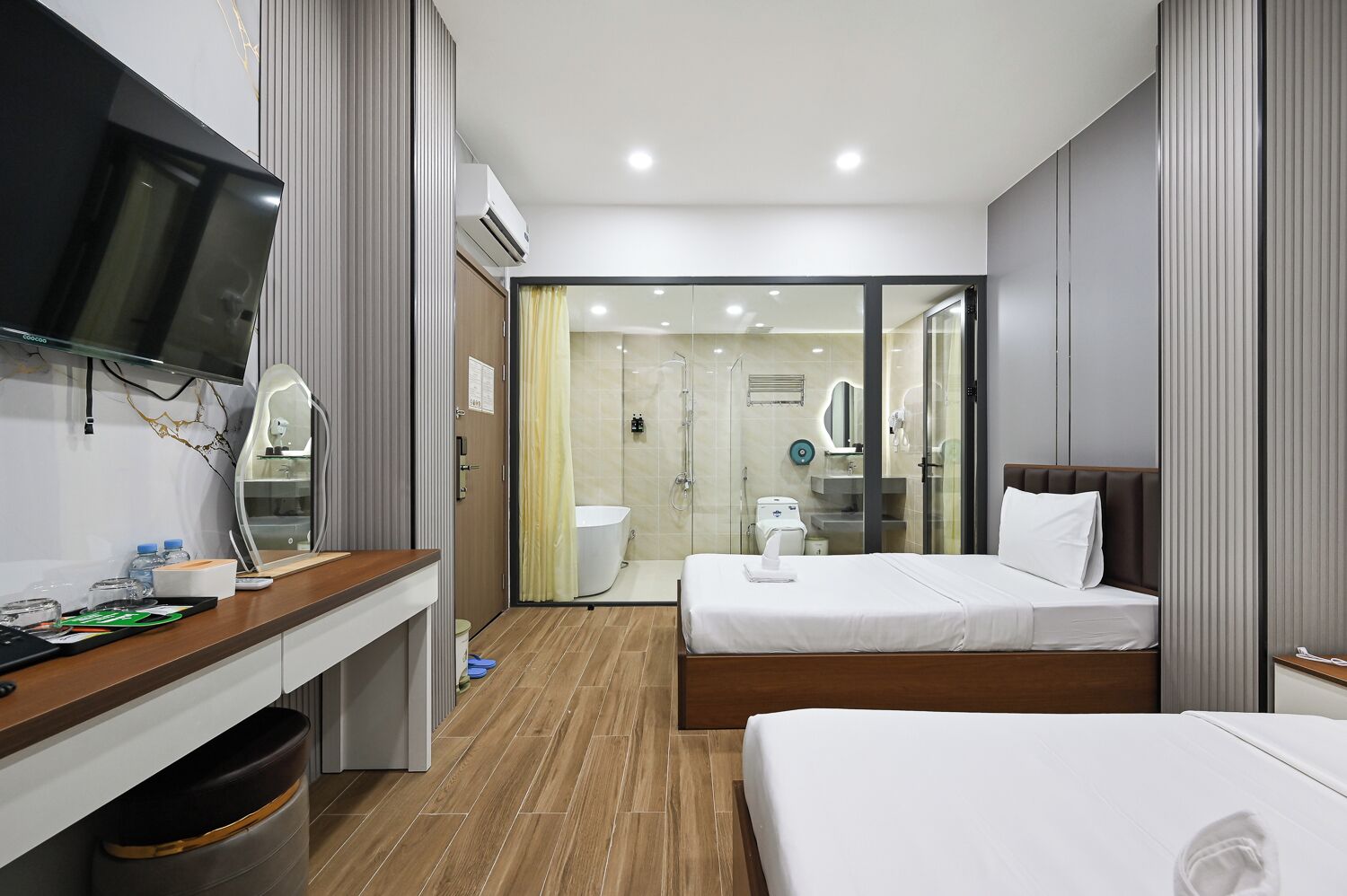 A hotel room with a bed, a desk, a TV, and a shower area.