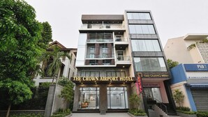 Un hotel moderno con un letrero destacado que dice 'THE CROWN AIRPORT HOTEL'.