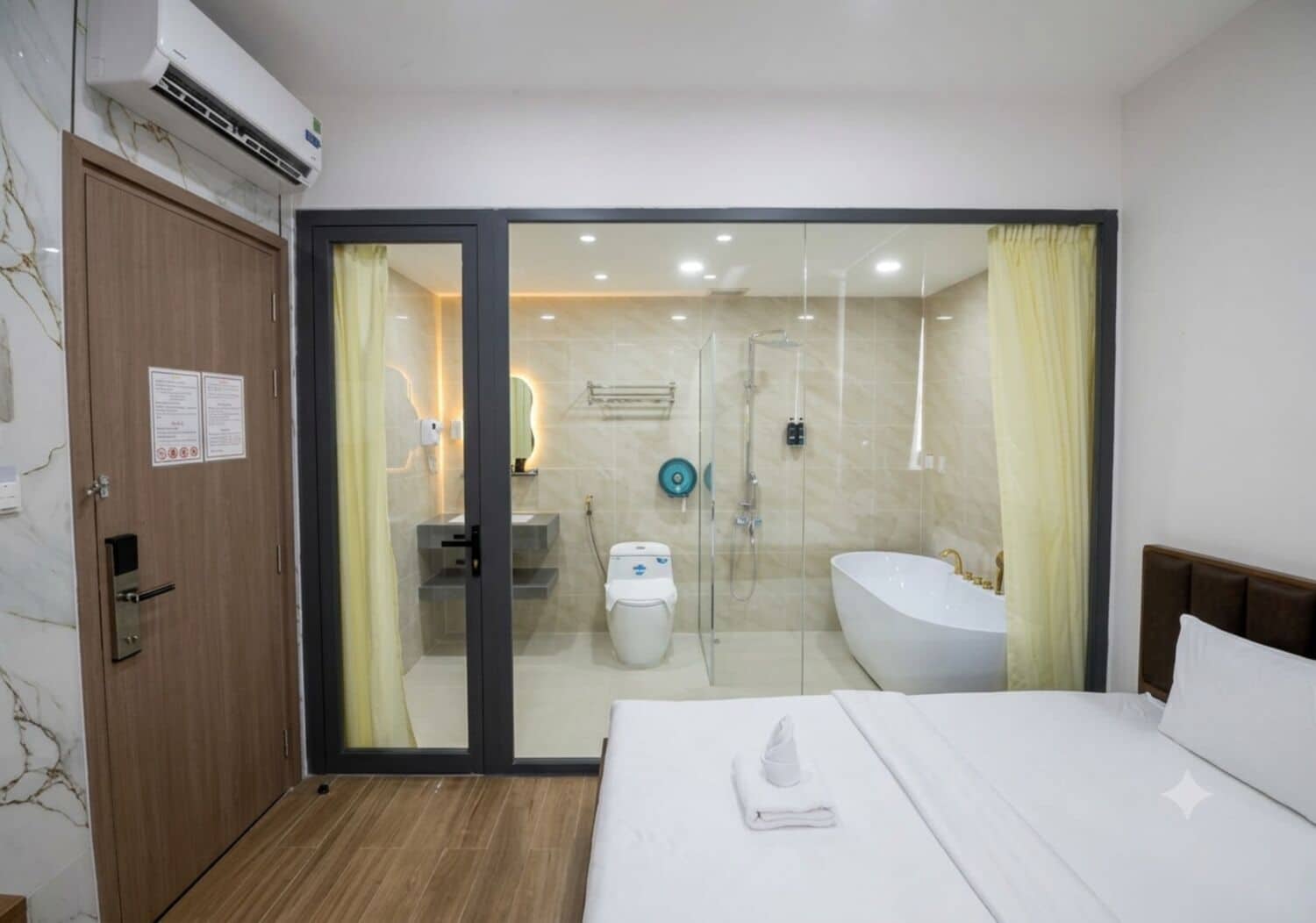 A hotel room with a bed, a bathroom with a shower, a toilet, and a sink.