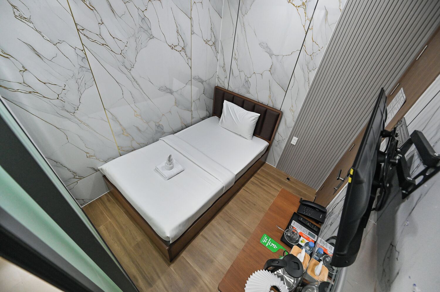 A compact room with a bed, a small table with a phone, and a bicycle.