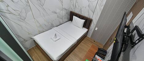 A compact room with a bed, a small table with a phone, and a bicycle.