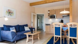 Ein Wohnzimmer mit Sofa, Couchtisch und einem Essbereich mit Stühlen und Tisch.