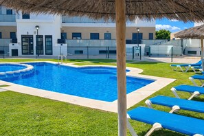Ein Schwimmbecken mit blauem Wasser, umgeben von Gras und blauen Liegestühlen.