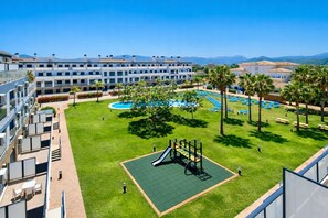 Ein Hotelinnenhof mit Spielplatz, Schwimmbad und Bergblick.