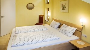 Ein Hotelzimmer mit Bett, Nachttisch, Lampe, Spiegel und Kunstwerk an der Wand.