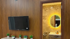 A modern bathroom with a mounted TV, a vanity with a mirror, and a wall-mounted air conditioner. - The Arlo Northeye 649 | Couple Friendly Stay in central Noida | Self Check-in (Noida)