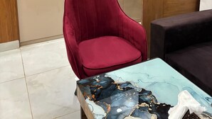 A modern kitchen with a microwave, kettle, and coffee maker. There is a red chair and a glass table with a marble pattern. - The Arlo Northeye 649 | Couple Friendly Stay in central Noida | Self Check-in (Noida)