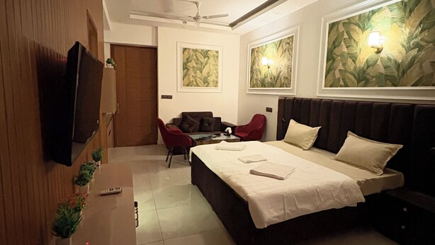 A hotel room with a bed, a desk, a TV, a ceiling fan, and artwork on the walls. - The Arlo Northeye 649 | Couple Friendly Stay in central Noida | Self Check-in (Noida)