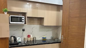 A modern kitchen with a microwave, kettle, and coffee maker on the countertop. - The Arlo Northeye 649 | Couple Friendly Stay in central Noida | Self Check-in (Noida)