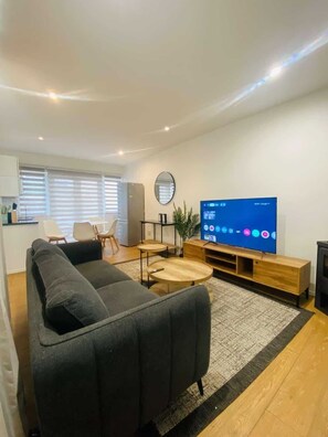 Ein modernes Wohnzimmer mit einer Couch, einem Couchtisch, einem Fernseher und einem kleinen Essbereich.