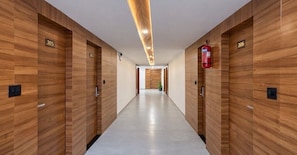 A hallway with wooden paneling, numbered doors, and a fire extinguisher. - Classic Add In Rooms (Bengaluru)