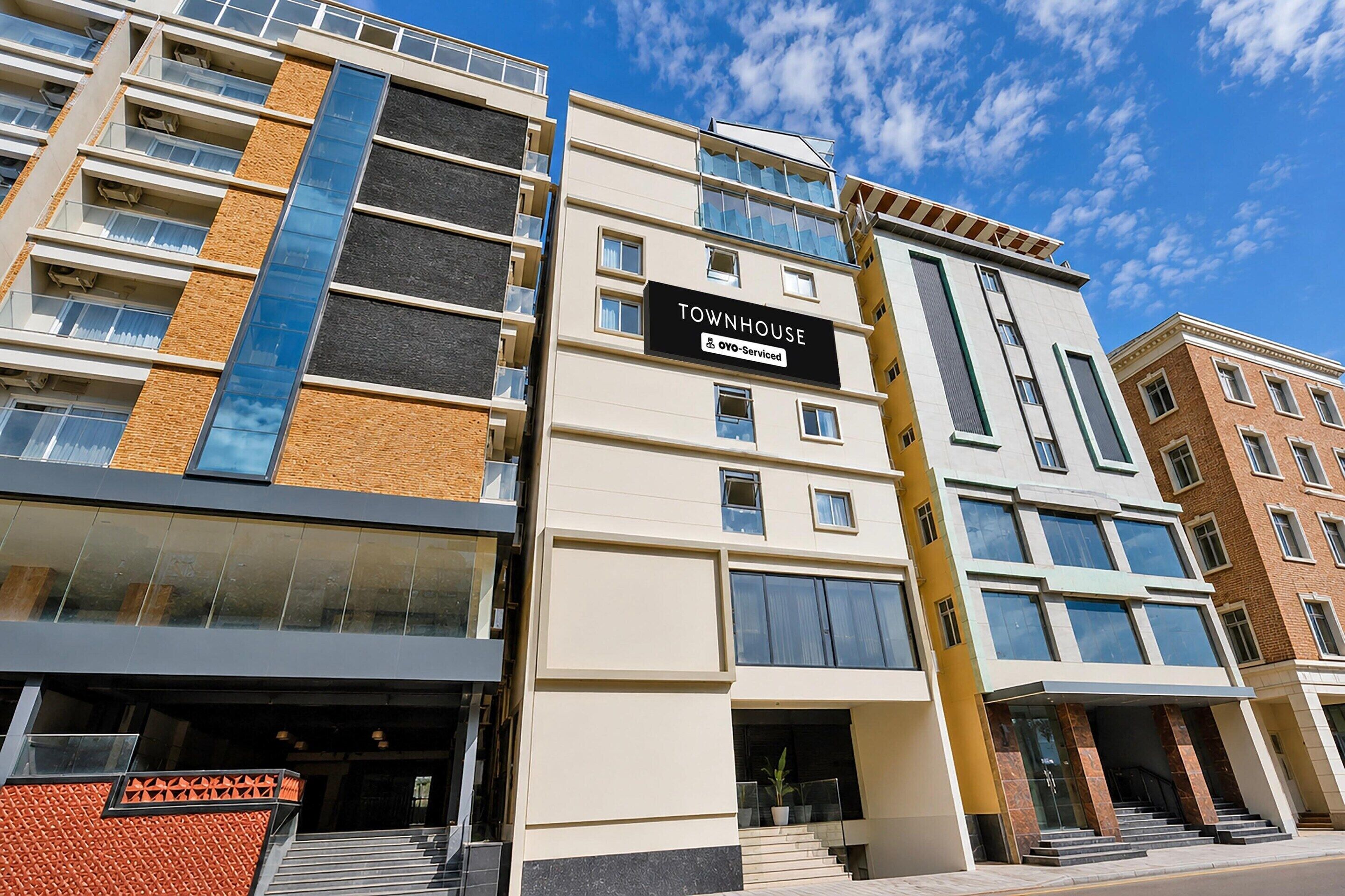 A multi-story building with a sign reading 'TOWNHOUSE' and 'OYO-Serviced.'