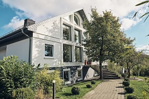 A modern two-story house with a paved driveway and a tree-lined entrance. - Bildstein's "Kathmandu" (Langenfeld, Deutschland)