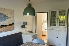 Ein Zimmer mit einem Bett, einem Schreibtisch, einer Lampe, einem Schrank mit Glastüren und einem Bild an der Wand.