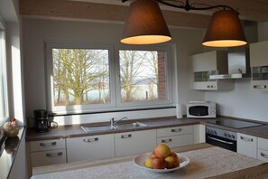 A modern kitchen with a large window, a sink, a microwave, and a stove. - Holiday apartment with 4 bedrooms (Greven)
