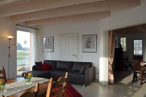 A living room with a sofa, dining table, chairs, and artwork on the walls. - Holiday apartment with 4 bedrooms (Greven)