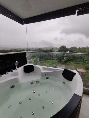 Ein Whirlpool mit Blick auf eine grüne Landschaft und Hügel.