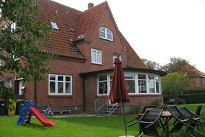 Ein Backsteinhaus mit rotem Dach, einer Rutsche für Kinder und einer Sitzgelegenheit im Freien.